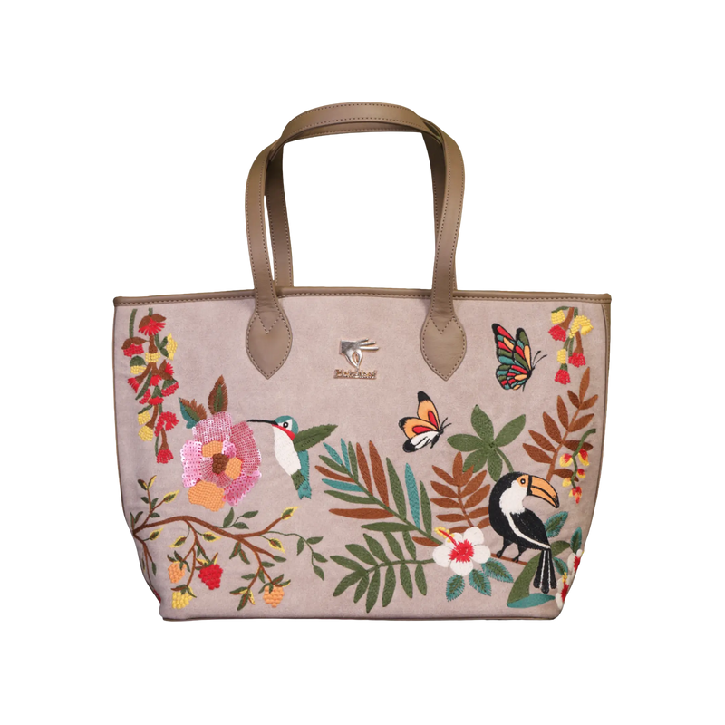 A beige tote bag with brown handles, decorated with colorful embroidered tropical motifs including a toucan, hummingbird, butterfly, flowers, and leaves. The brand name 'Beach Road' is embroidered on the front.